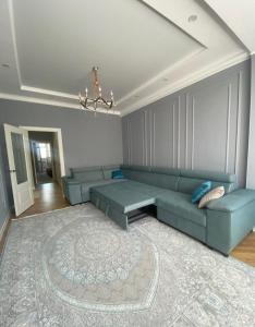 een woonkamer met een blauwe bank en een tapijt bij Двухкомнатая элитка Дордой Плаза in Bisjkek