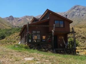 uma casa numa colina com montanhas ao fundo em Tierras Bayas Mountain Refuge em Los Cipreses
