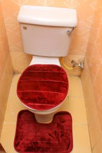 um WC com um assento vermelho numa casa de banho em Kate's 1 bedroom furnished apartment em Kisumu