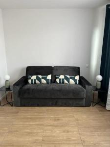 a black couch with pillows in a living room at cosy moderne chaleureux équipé proche tram in Talence