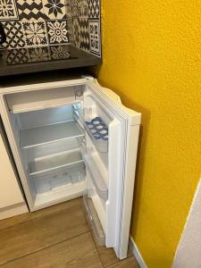 un réfrigérateur vide avec sa porte ouverte à côté d'un mur dans l'établissement cosy moderne chaleureux équipé proche tram, à Talence
