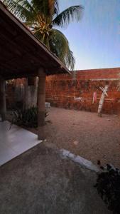 een patio met een bakstenen muur en een palmboom bij Casa Temporada Beberibe in Beberibe