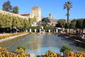 una fuente en un jardín con un edificio en el fondo en Precioso Loft El Arcángel II junto a la Ribera en Córdoba