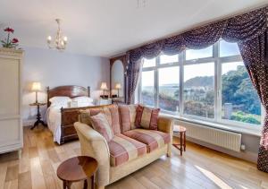 a bedroom with a bed and a couch and a large window at Kilmorie Lodge in Torquay