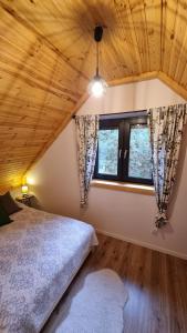 um quarto com uma cama e duas janelas em Domek Leśny Spokój Smyków em Celiny