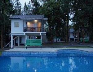a house with a green bench next to a swimming pool at Misty Dam Wayanad Premium Resort With Banasura Dam View in Padinjarathara