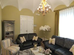 una sala de estar con 2 sofás y una lámpara de araña. en Hotel Boutique IULIA 5 Estrellas Premium en Zafra