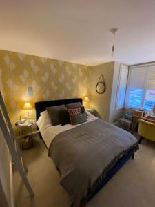a bedroom with a large bed and a yellow wall at Charming & Spacious 2BD House wGarden - Wimbledon in Raynes Park