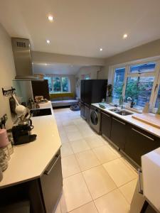 a large kitchen with a sink and a dishwasher at Charming & Spacious 2BD House wGarden - Wimbledon in Raynes Park