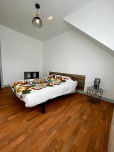1 dormitorio con 1 cama grande y suelo de madera en MAISON DE VILLE, en La Haye-du-Puits