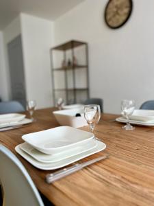 La Haye-du-Puits的住宿－MAISON DE VILLE，木桌,带盘子和玻璃杯,钟