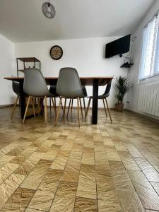 ein Esszimmer mit einem Tisch und Stühlen auf einem Holzboden in der Unterkunft MAISON DE VILLE in La Haye-du-Puits