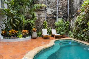 uma piscina num pátio com duas cadeiras e plantas em Hotel Casa La Mantilla by Faranda Boutique em Cartagena das Índias