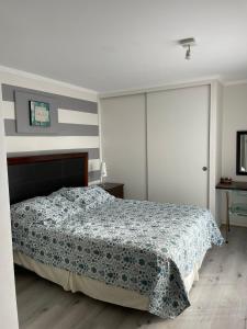 1 dormitorio con 1 cama con manta azul y blanca en Condominio Parinacota, en Arica
