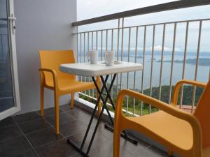 een tafel en stoelen op een balkon met uitzicht bij Blowing in the Wind - Lake View Apartments in Tagaytay