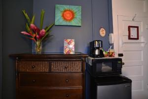 a dresser with a microwave and a vase with flowers on it at Wailuku Guesthouse in Wailuku