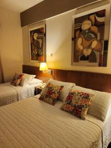 a hotel room with two beds and paintings on the wall at Hotel Maria in Encarnación