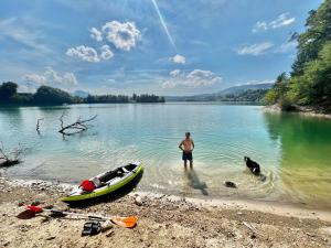 a man standing in the water with a boat and a dog at Entire modern villa with outdoor swimming pool! in Treyvaux