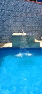 uma fonte numa piscina de água azul em Casa Mongagua em Mongaguá