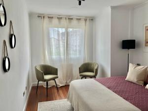 1 dormitorio con 1 cama, 2 sillas y ventana en Nuevo Piso en Couto, en Ourense