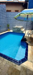 uma piscina azul com um guarda-sol e uma mesa em Casa Mongagua em Mongaguá