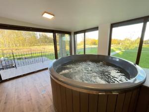 a large bath tub in a room with windows at Kukorica Csárda Apartman 2 in Balatonújlak