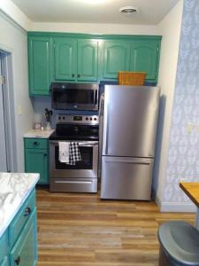 a kitchen with green cabinets and a stainless steel refrigerator at Cozy Getaway in Lincoln! 
