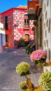 ein rotes Gebäude mit Blumen davor in der Unterkunft Rural Suite Santiago de Tunte in San Bartolomé de Tirajana