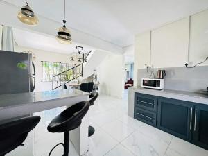 a kitchen with white cabinets and black stools in it at Villa Calodyne in Goodlands
