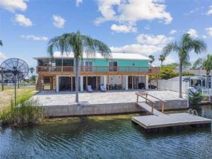 a house on the water with a dock and palm trees at Huge discounts though end of the 2023! in Hernando Beach