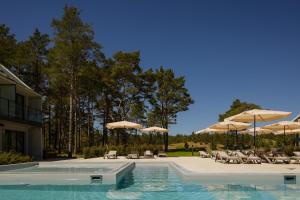 a swimming pool with chairs and umbrellas at Saltic Resort & Spa Łeba in Łeba