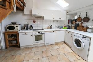 a kitchen with white cabinets and a washer and dryer at Rare pearl with garden facing the sea in Saint-Coulomb