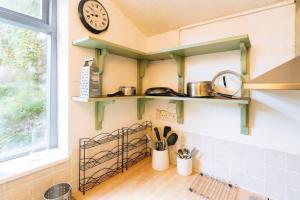 a kitchen with green shelves and a clock on the wall at Peaceful 2BD Home - 18 mins to Bath City Centre! in Bath