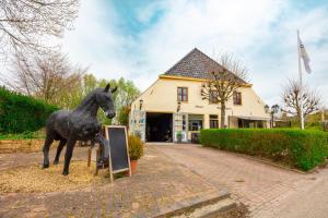 una estatua de un caballo de pie junto a una señal en De Oude Smidse, en Westernieland