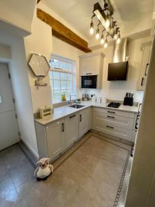 a kitchen with white cabinets and a teddy bear sitting on the floor at Castle Yard Cottage in Knaresborough