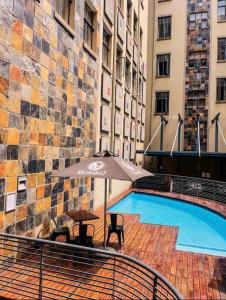 Johannesburg的住宿－Budget Friendly Private with WiFi 3km to Maboneng，一座带遮阳伞的游泳池位于大楼旁