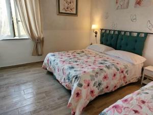 um quarto com 2 camas e uma colcha com flores em Casa di Campagna em Ronciglione