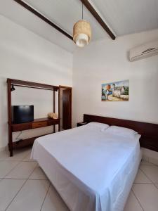 a bedroom with a large white bed and a tv at D'Ajuda Inn in Arraial d'Ajuda