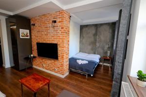 a room with a brick wall with a bed and a tv at Przytulnie z The GG Apartments in Poznań