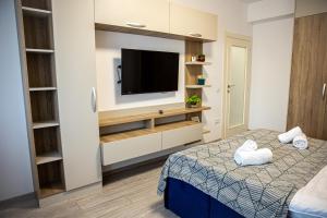 een slaapkamer met een bed en een tv aan de muur bij Q Elegance Palas Mall in Iaşi
