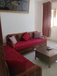 uma sala de estar com um sofá vermelho e uma mesa em maison a louer a la grotte de bizerte em Dar el Koudia