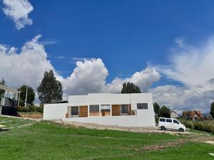 een wit huis met een auto ervoor geparkeerd bij Casa El Roble paipa in Paipa