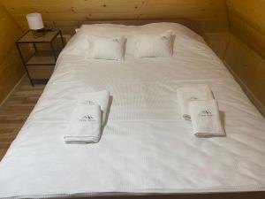 a white bed with two white towels on it at Brvnare Golo Brdo in Mokra Gora