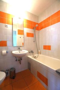 y baño blanco y naranja con lavabo y bañera. en Thomas apartment 028 en Liubliana