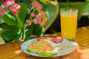 a plate of food with a hot dog and a glass of orange juice at Alojamiento San Martín in San Andrés
