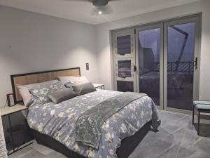 1 dormitorio con 1 cama grande y balcón en UMDLOTI MODERN 3 BEDROOM BEACH FLAT, en Umdloti
