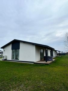 a white house with a black roof in a field at Marupe Saules in Mārupe