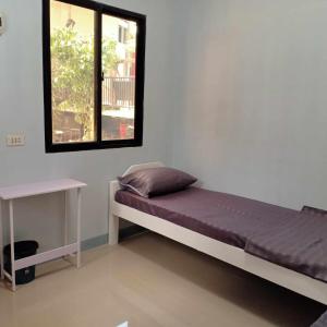 a bedroom with a bed and a window and a table at JJP Dormitel in Molave