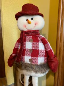 un muñeco de nieve de peluche con un abrigo y un sombrero rojos en La Voz del Silencio, en Neril