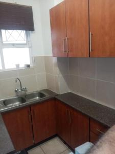 a kitchen with wooden cabinets and a sink at Happy days in Amanzimtoti